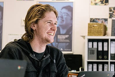 Smiling male student in class with laptop